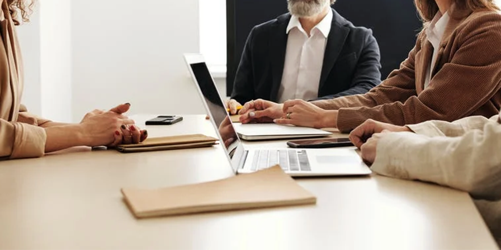 Photo of several people at a table interviewing and another person